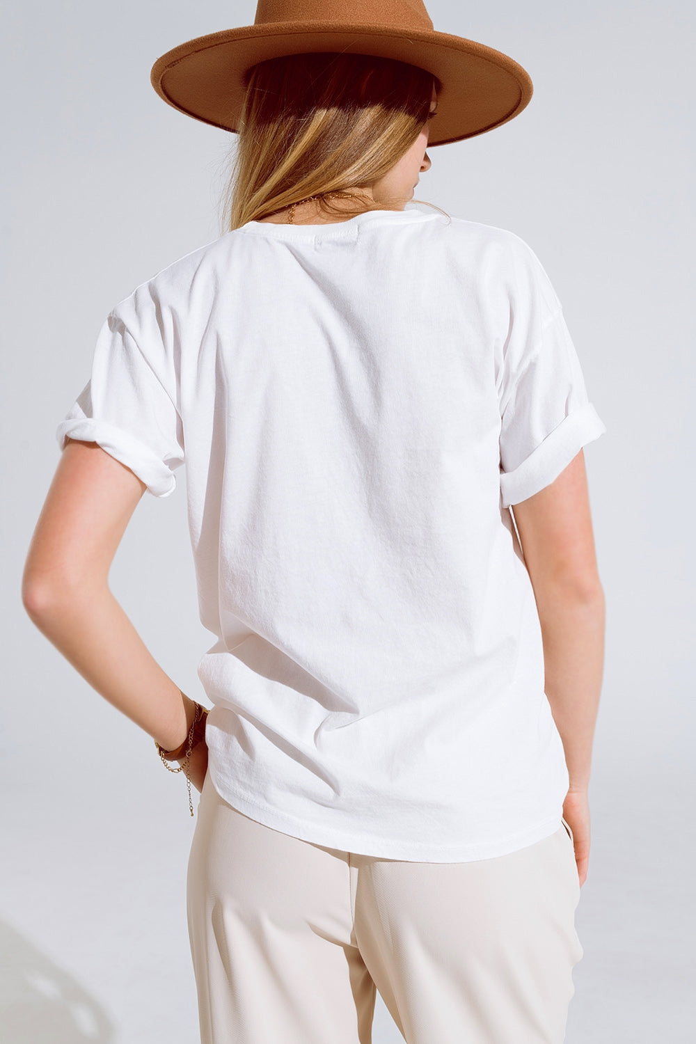 Camiseta crema con logotipos de nombres famosos en la parte delantera