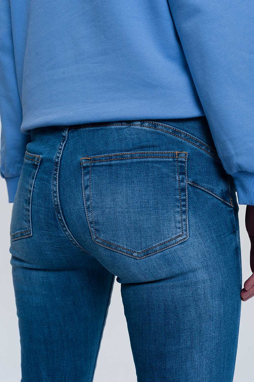 jeans ajustados de mezclilla clara con tobillos doblados y detalle rasgado
