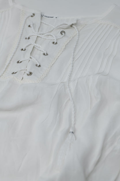 Camisa blanca con extremos de borla y cierre de lazo cruzado
