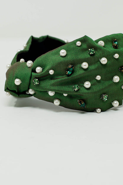 Diadema adornada con joyas blancas y verdes con un nudo en el centro.