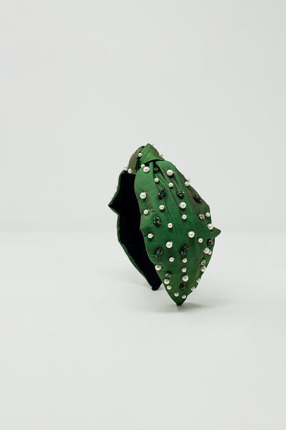 Diadema adornada con joyas blancas y verdes con un nudo en el centro.