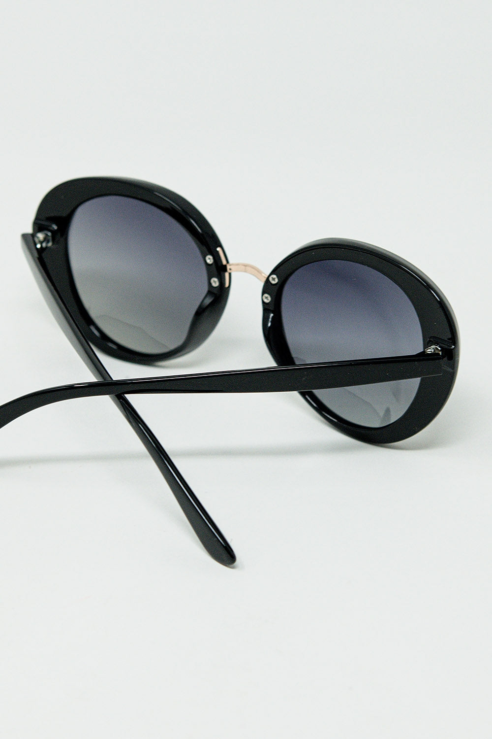 Gafas de sol ovaladas negras con detalle metálico dorado