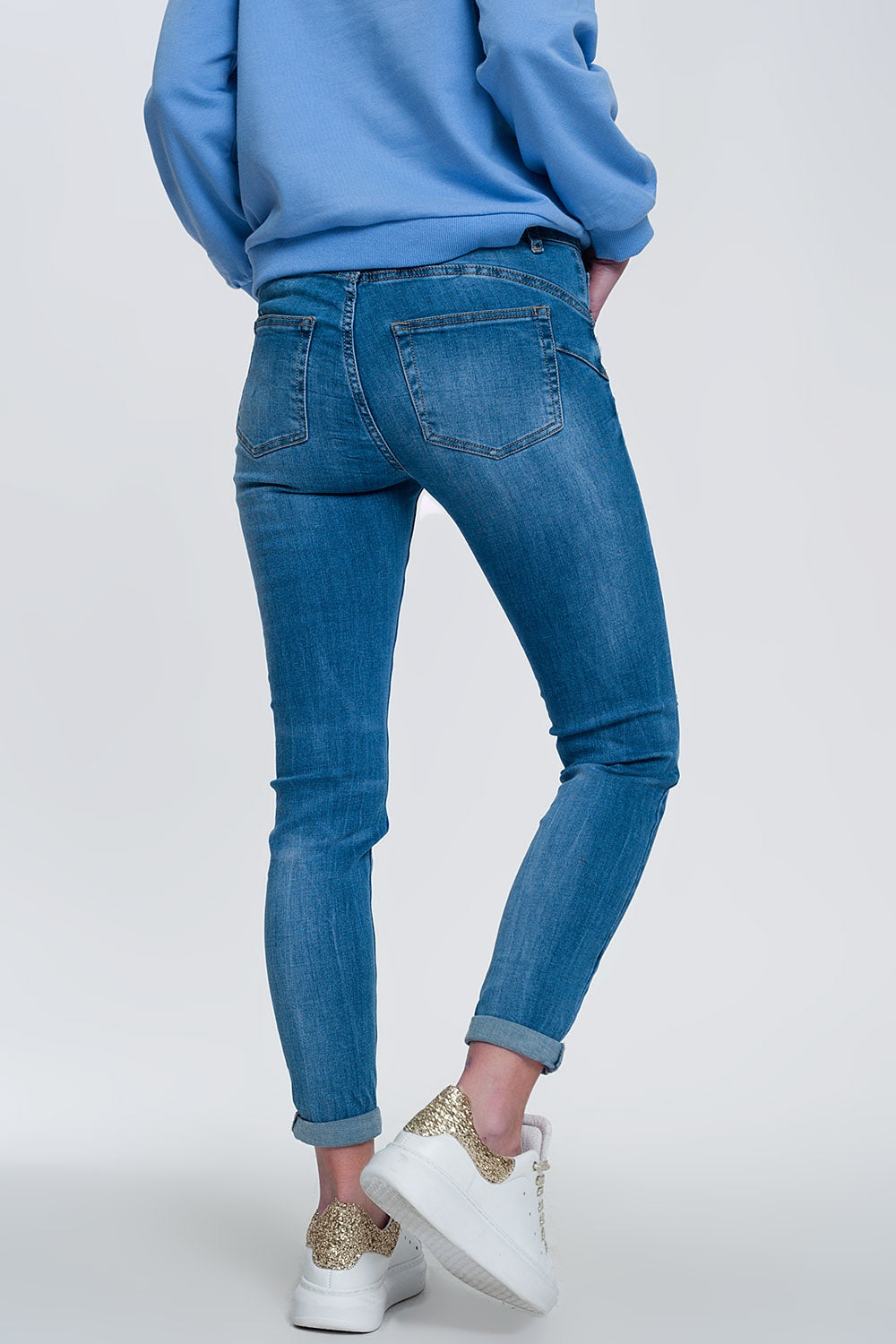 jeans ajustados de mezclilla clara con tobillos doblados y detalle rasgado
