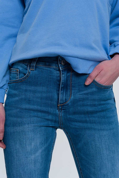jeans ajustados de mezclilla clara con tobillos doblados y detalle rasgado