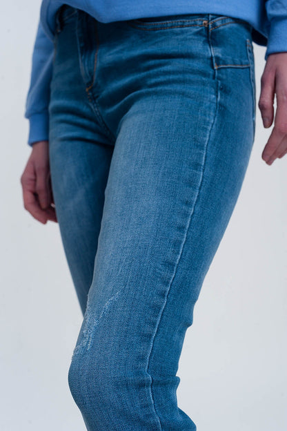 jeans ajustados de mezclilla clara con tobillos doblados y detalle rasgado
