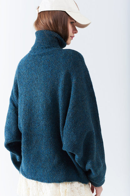 Suéter oversize en color verde azulado con cuello alto y mangas sueltas.