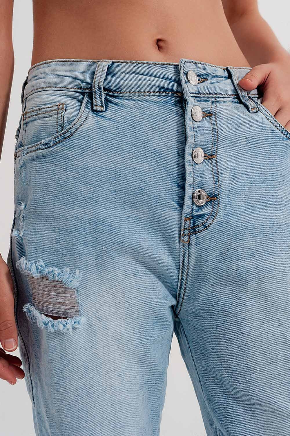 Vaqueros azul claro desgastados de pernera recta con rotos y detalle de botones